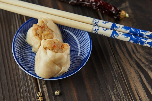 Chinese meat dumpling steamed dish with chopsticks and dimsum.