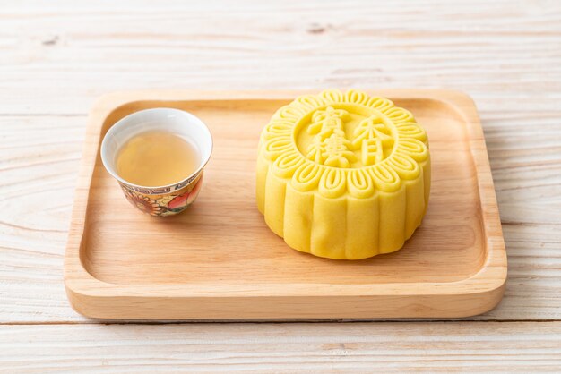 Chinese moon cake custard flavour with tea on wood plate