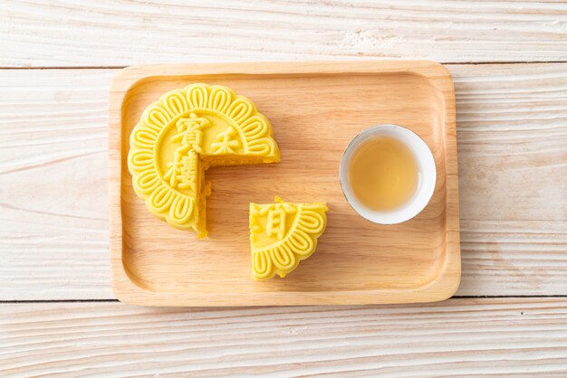 Chinese moon cake custard flavour with tea on wood plate