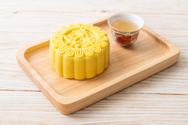 Chinese moon cake custard flavour with tea on wood plate