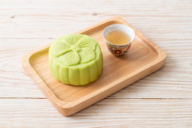 Chinese moon cake green tea flavour with tea on wood plate