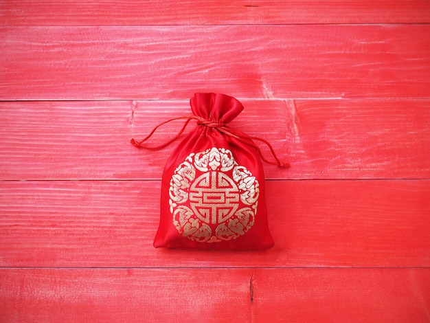 Chinese New Year background. Red silky money bag with string on natural pine wood background and copy space.