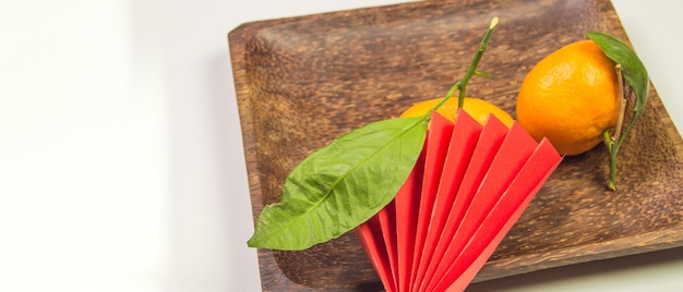 Capodanno cinese, composizione con mandarini, divertenti origami di carta rossa su un piatto di legno scuro su sfondo bianco, spazio per il testo a sinistra