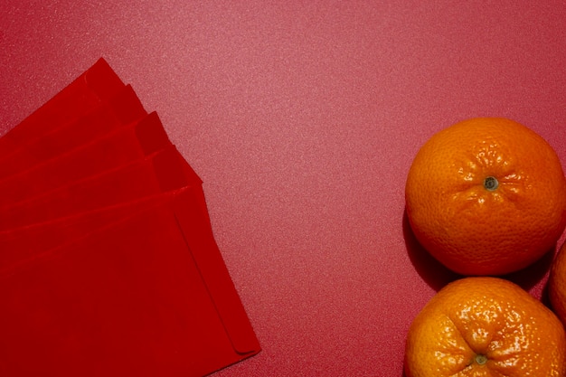 Chinese new year concept - mandarin oranges and red packet on red background