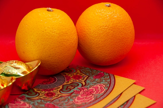 Chinese New Year decoration with oranges colorful packets and gold ingots on red cover background Chinese festive season concept