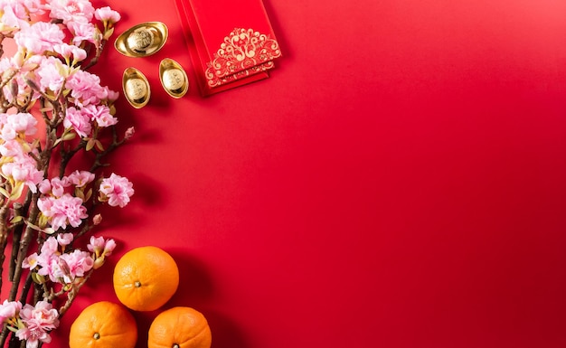 Photo chinese new year decorations made from red packet, orange and gold ingots or golden lump on a red background. chinese characters fu in the article refer to fortune good luck, wealth, money flow.