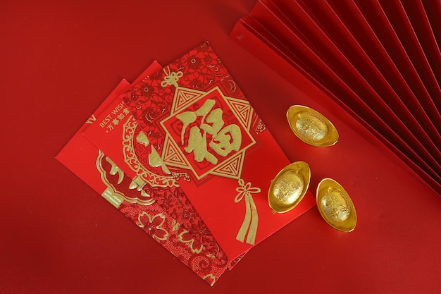 Chinese new year festival decorations, ang pow, red packet and gold ingots on red background.