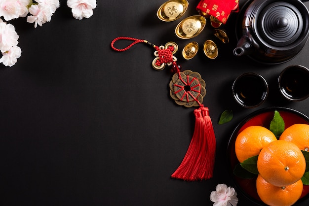 Chinese new year festival decorations pow or red packet, orange and gold ingots or golden lump on a black background.