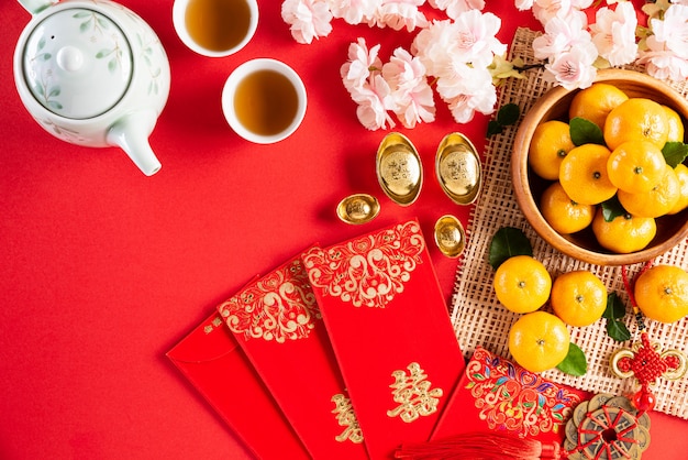 Chinese new year festival decorations pow or red packet, orange and gold ingots or golden lump on a red background. Chinese characters FU in the article refer to fortune good luck, wealth, money flow.