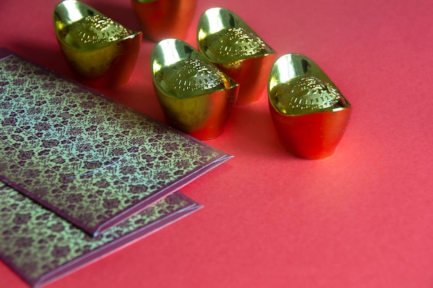 Китайские новогодние пакеты с китайскими золотыми слитками на красном фоне Концепция китайского нового года
