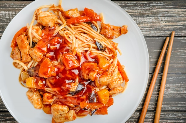 Chinese noodle in sour-sweet sauce and chopsticks on table