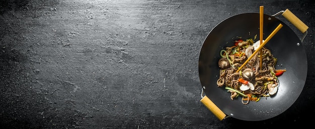 Chinese noodles wok soba in a frying pan with chopsticks