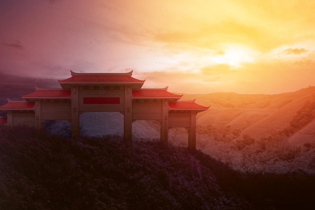 Chinese pavilion gate with red roof on the hill with dramatic sky background