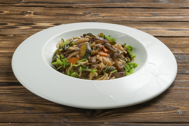 Chinese rijstnoedels wok met rundvlees, groenten en groene uien.