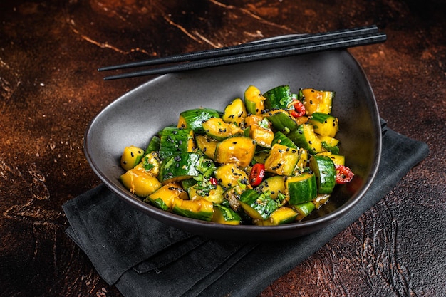 Chinese smashed cucumbers with herbs and sesame oil Dark background Top view