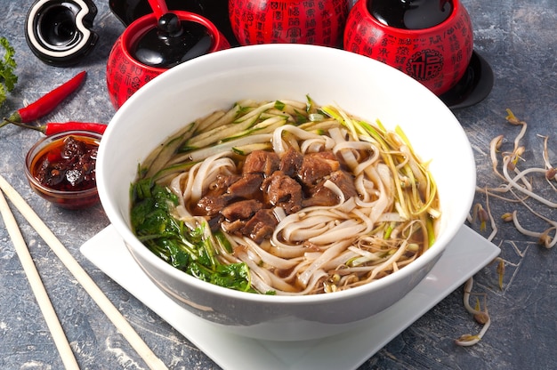 Photo chinese soup with veal rice noodles cucumber and herbs