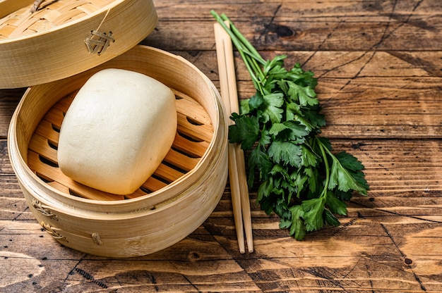 Photo chinese steamed buns in traditional bamboo steamer. wooden background. top view. copy space.