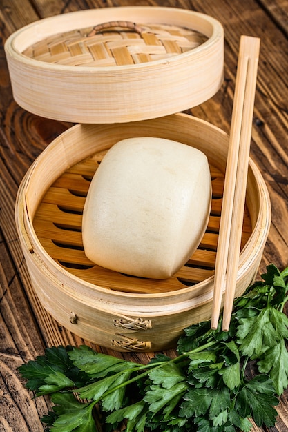 Photo chinese steamed buns in traditional bamboo steamer. wooden background. top view.