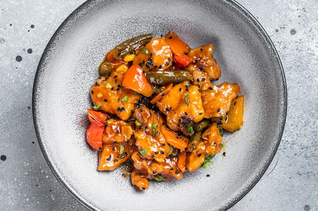 Chinese Sweet and Sour Pork guo bao rou in a bowl Gray background Top view