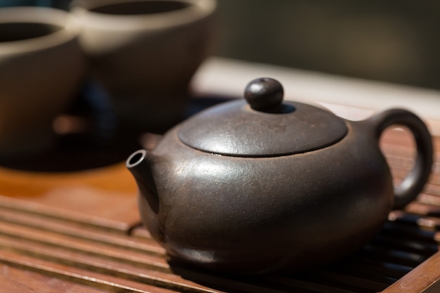 Китайская чайная церемония. Керамический чайник из глины и чаш на деревянном фоне.