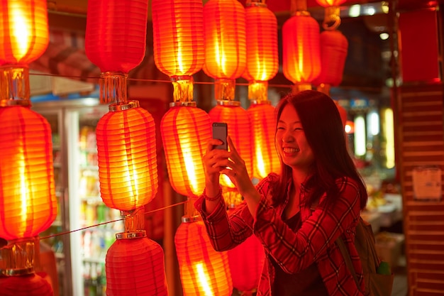 Chinese tiener met mobiele telefoon in de buurt van Chinese nieuwjaarslantaarns