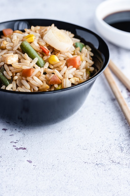 Chinese Vegetable Fried Rice and eggs served in a bowl with chopsticks and sauce soy. Chinese Cuisine