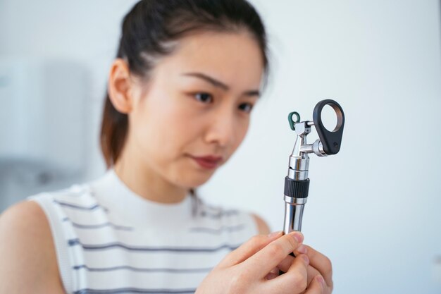 Chinese veterinary assistant using a magnifying glass. White health clinic.