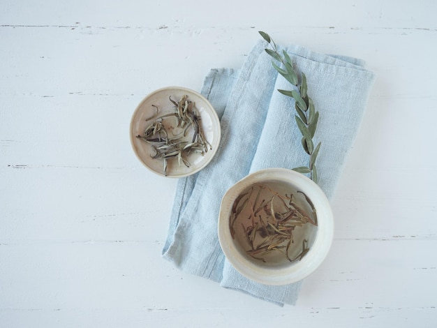 Foto chinese witte thee genaamd zilveren naald of bai hao yinzhen gedroogde bladeren op bord en kopje warme thee