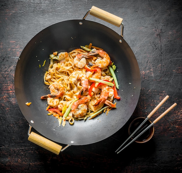 Foto wok cinese udon noodles in una padella wok con bacchette e salsa di soia