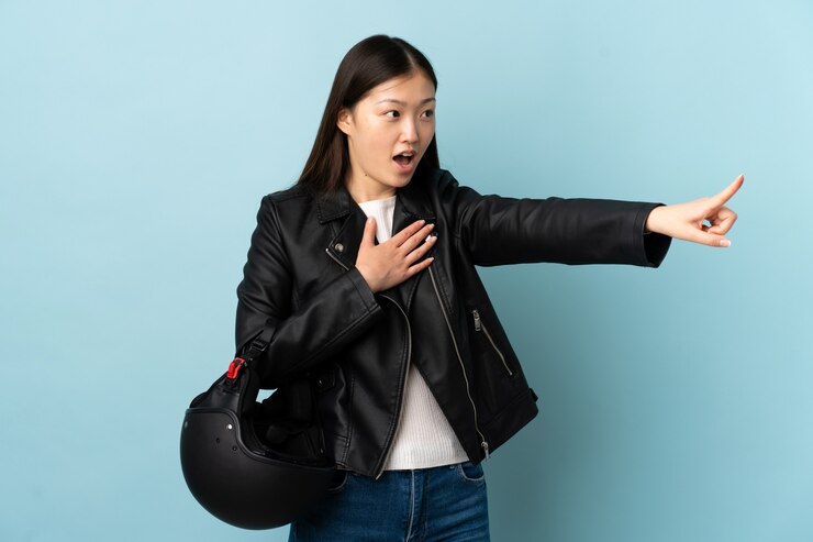 Photo 分離された青い壁人差し指を側にオートバイのヘルメットを保持している中国の女性