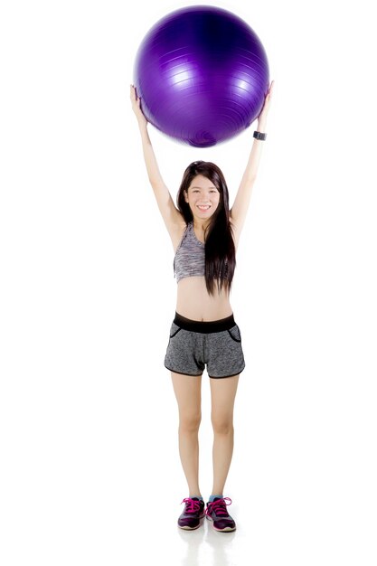 Chinese woman lifting a fitness ball on studio