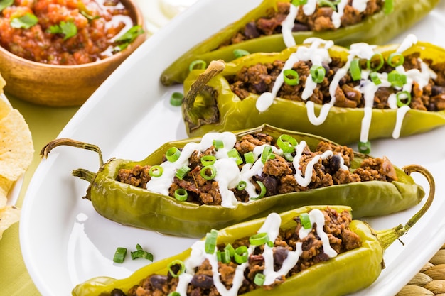 Chipotle beef & bean stuffed chili peppers garnished with sour cream and scallions.