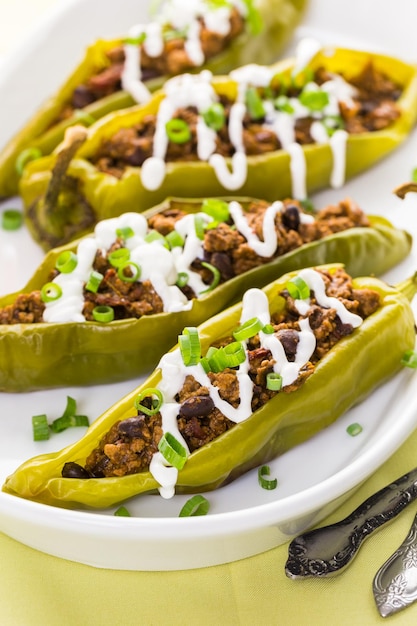 Chipotle beef & bean stuffed chili peppers garnished with sour cream and scallions.