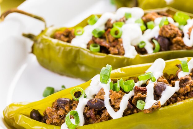 Chipotle beef & bean stuffed chili peppers garnished with sour cream and scallions.