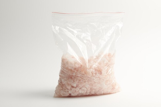 Chipped Himalayan pink salt stone in zip bag isolated on white background