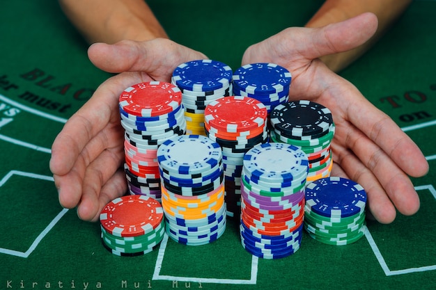 Чипсы и карты для покера в руке на зеленом столе
