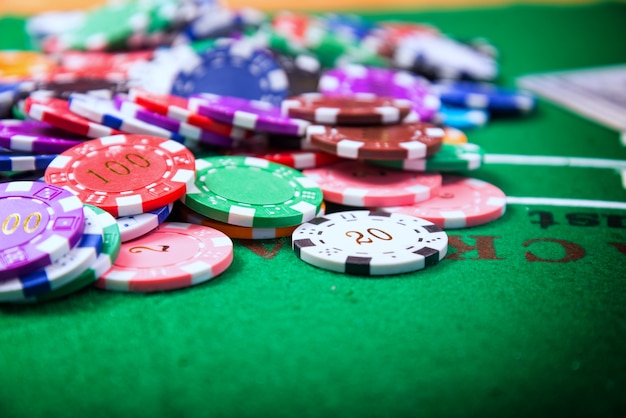 緑色のテーブルに置かれたカラフルなカジノのチップは、カジノで賭けるのに使用されるコインです