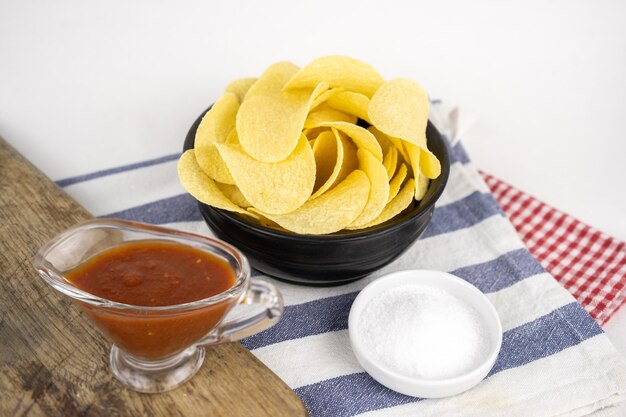 Chips in een houten kom met barbecuesaus en zout