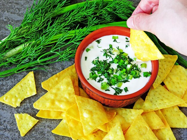 Photo chips nachos with sour cream sauce and greens.