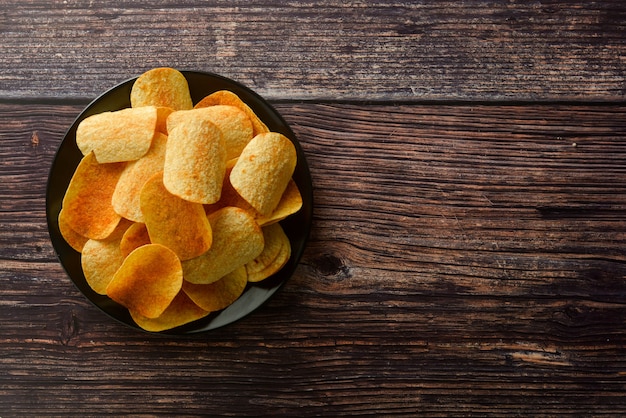 Chips over houten achtergrond. Zoute knapperige snack. Ruimte kopiëren.