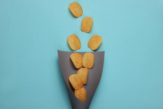 Chips plakjes in papieren zak op blauw