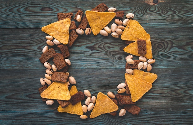 Chips, salted crackers and pistachios on a blue wood.