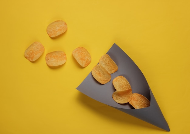 Фото Ломтики чипсов в бумажном пакете на желтом