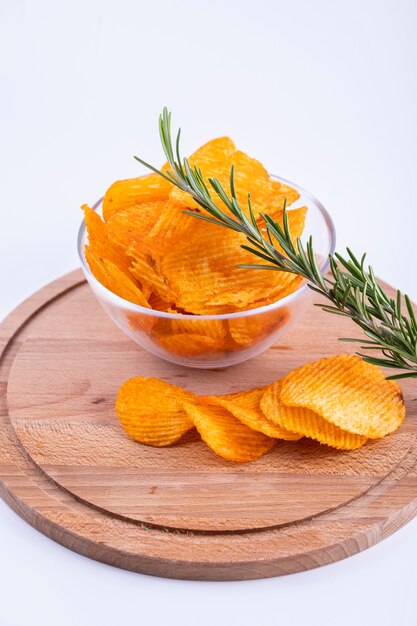 Chips a sprig of rosemary in a glass bowl on a wooden board