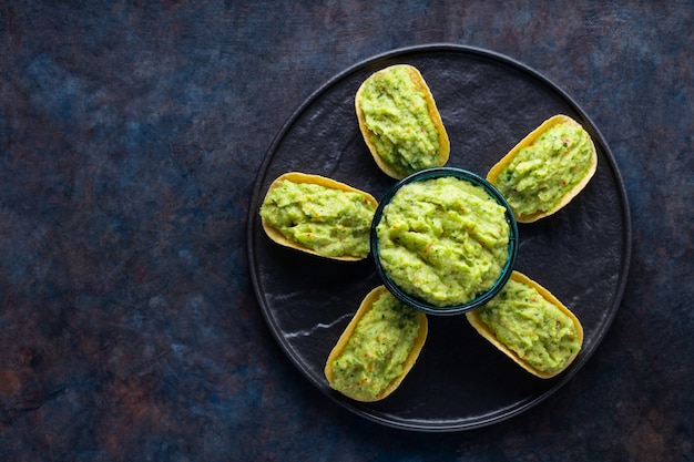 Photo chips with guacamole on a black plate