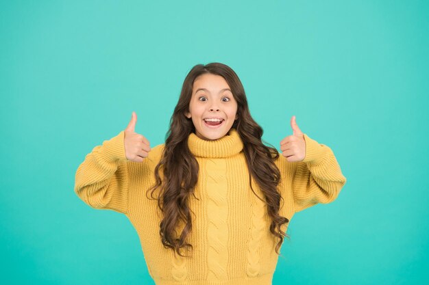 Chique, knusse stijl kind in casual winter mode-stijl Klein meisje met lang donkerbruin haar Pure schoonheid van babymeisje breien voor kinderen succesvol meisje Toon duim omhoog gelukkige jeugd