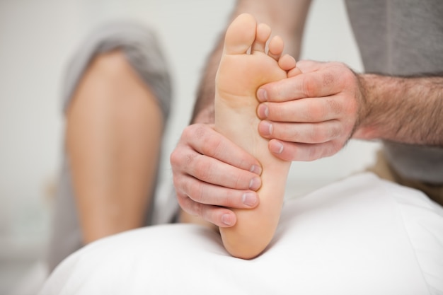 Photo chiropodist palpating the sole of the foot of a patient