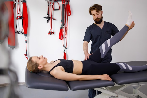 Chiropractor stretches a female patient leg