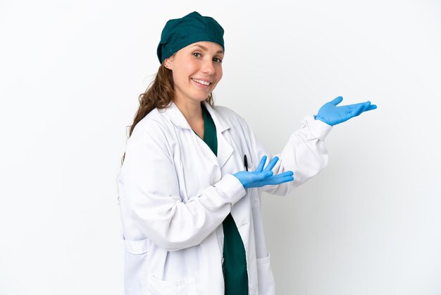 Chirurg blanke vrouw in groen uniform geïsoleerd op een witte achtergrond die de handen naar de zijkant uitstrekt om uit te nodigen om te komen