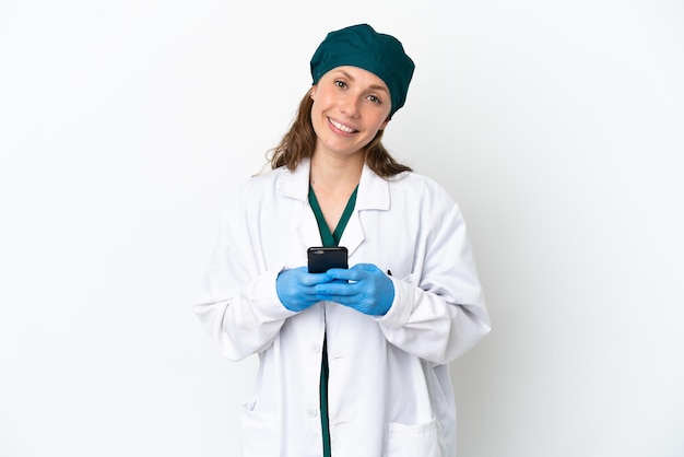 Chirurg blanke vrouw in groen uniform geïsoleerd op een witte achtergrond die een bericht verzendt met de mobiel